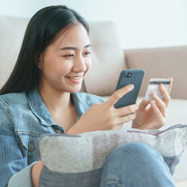 Woman uses a credit card to make a purchase via her mobile phone.