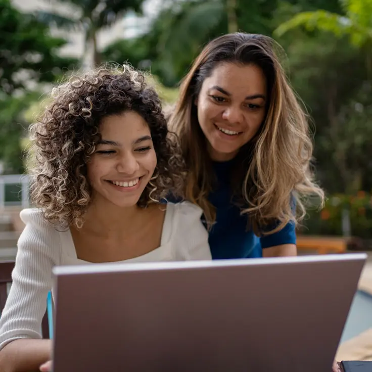 Two young women working on a laptop.