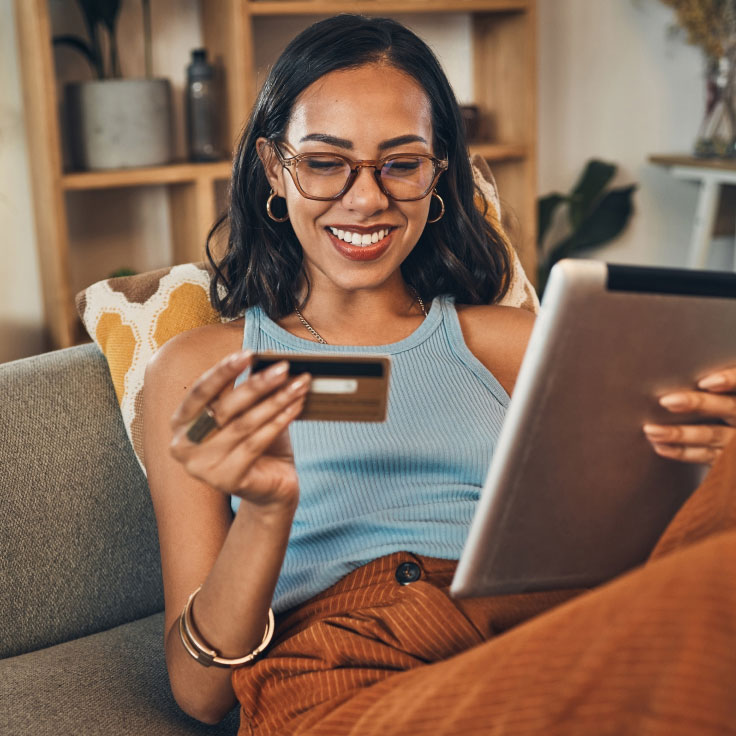 Woman making a purchase with her credit card while shopping on her tablet.