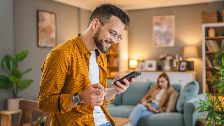 Man making a purchase on his mobile phone via the comfort of his living room.