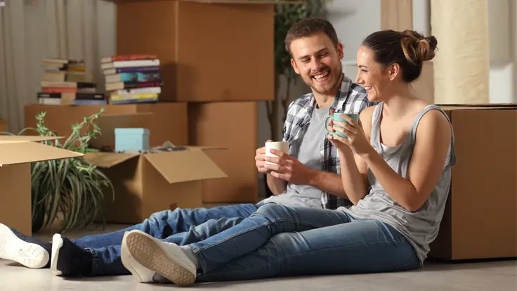 Happy couple takes a rest while unpacking boxes in their new home.