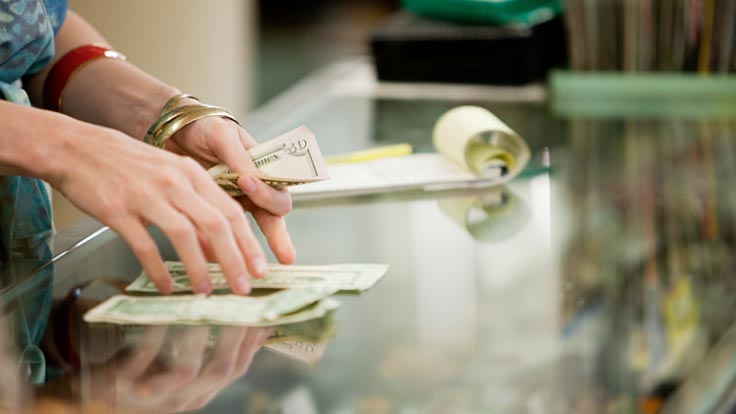 Women counting cash at a store counter.